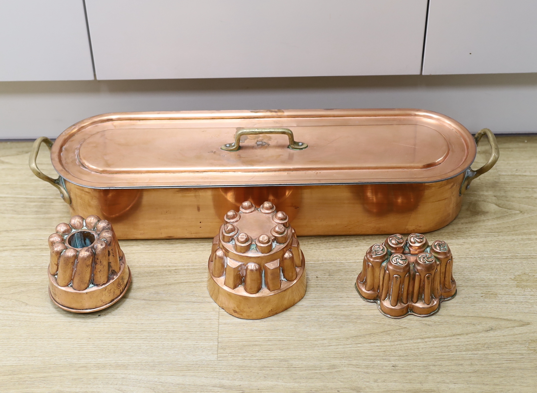 A copper fish kettle and three copper jelly moulds, largest 68.5cm